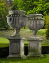 A PAIR OF LARGE AND IMPRESSIVE CARVED LIMESTONE GARDEN URNS ON PLINTHS IN IMPERIO TASTE, LATE 20TH CENTURY