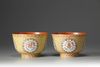 A pair of coral-red and yellow ground bowls with famille rose decoration
