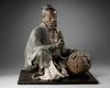 A JAPANESE SEATED LEGENDARY FIGURE WITH HAY BALE, 18TH CENTURY