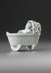 A WHITE DELFT MODEL OF A BABY IN A CRADLE, END OF 18TH CENTURY
