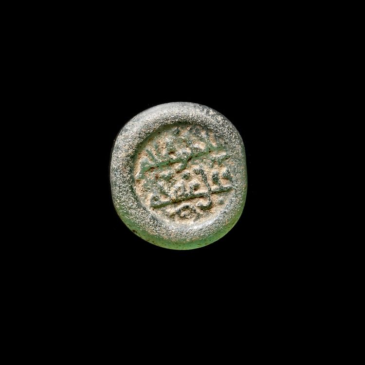 A FATIMID GLASS WEIGHT OF HALF DIRHAM, AL-HAKIM BI-AMR ALLAH (386AH-411AH/ 996AD-1021AD)