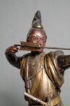 A bronze figure of a Samurai warrior resting on one knee while tensioning a bow