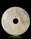 A CHINESE BI DISC DECORATED WITH A BORDER OF FOUR ANIMAL HEADS INTERTWINED TO FORM A PATTERN, LATE EASTERN ZHOU OR HAN PERIOD (c.471-221 BC)