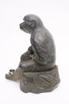 A large Japanese bronze figure of a monkey sitting on a rock with a persimmon in its hand