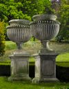 A PAIR OF LARGE AND IMPRESSIVE CARVED LIMESTONE GARDEN URNS ON PLINTHS IN IMPERIO TASTE, LATE 20TH CENTURY
