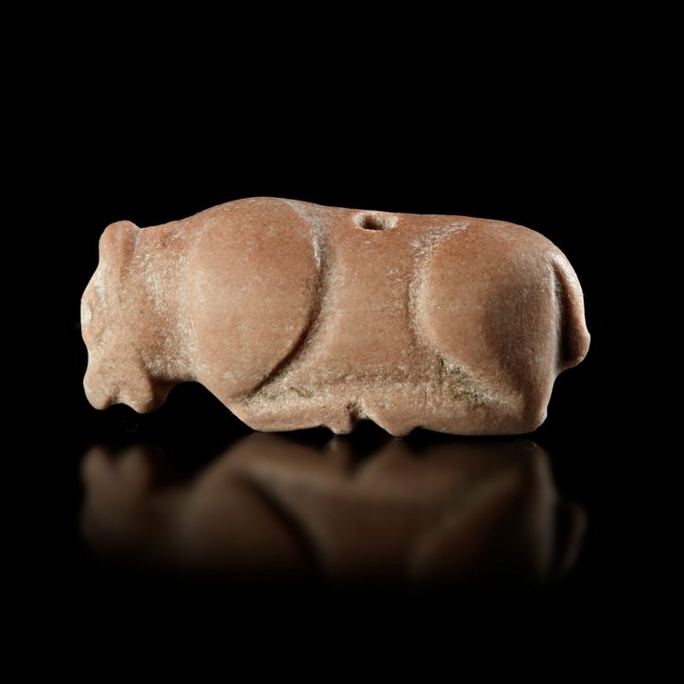 A STAMP SEAL IN THE SHAPE OF A BULL RECLINING TO THE LEFT IN PINK CALCITIC LIMESTONE, 3RD MILLENNIUM BC