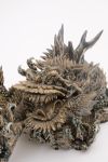 A ceramic figure of a dragon resting on its claws  and a wide open mouth and inlayed eyes