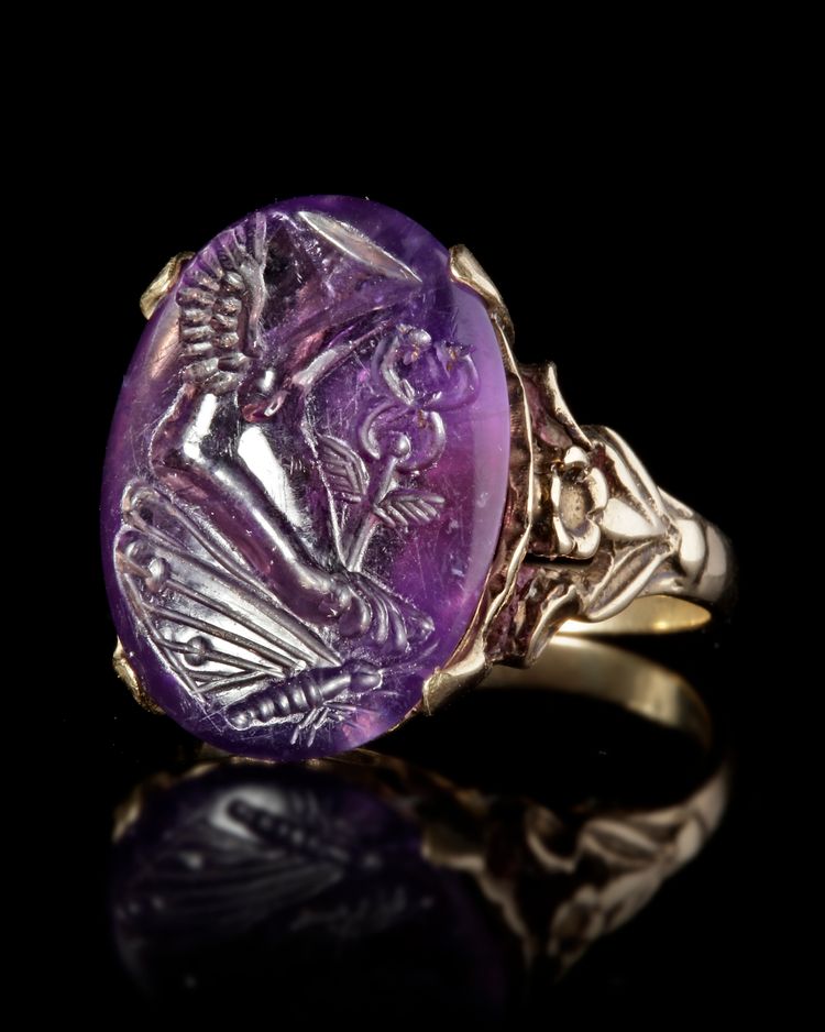 A ROMAN INTAGLIO IN AMETHYST WITH A FOOT OF MERCURY AND BUTTERFLY MOUNTED IN A 19TH CENTURY RING, INTAGLIO 1ST CENTURY BC-AD