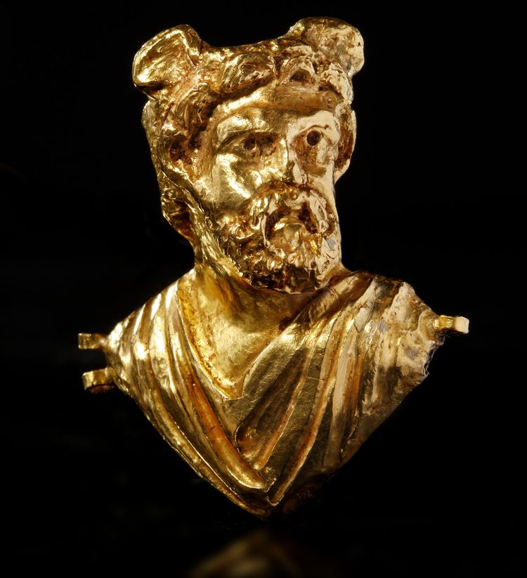 A ROMAN REPOUSSÉ GOLD BUST OF A MAN WITH WINGED HEAD, CIRCA 2ND CENTURY A.D.
