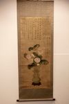 A Chinese hanging scroll depicting a vase with flowers and Chinese calligraphy