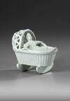 A WHITE DELFT MODEL OF A BABY IN A CRADLE, END OF 18TH CENTURY