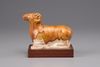 An earthenware figure of a ram on a wooden base