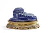 A Chinese lapis lazuli carving of a Buddhist lion on a gilt bronze champlevé enamel stand