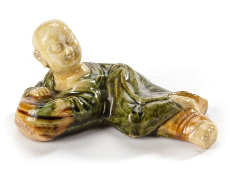 A CHINESE SANCAI CERAMIC BRUSH REST IN THE FORM OF A RECUMBENT BOY, SONG DYNASTY (960-1279)