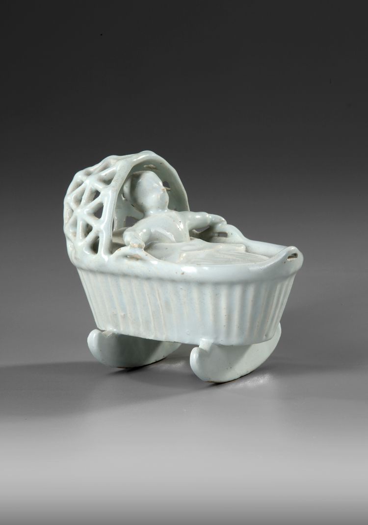 A WHITE DELFT MODEL OF A BABY IN A CRADLE, END OF 18TH CENTURY