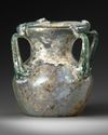 A ROMAN FOUR-HANDLED GREEN GLASS JAR, CIRCA 3RD CENTURY A.D.