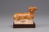 An earthenware figure of a ram on a wooden base