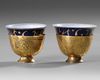 TWO OTTOMAN GILDED TOMBAK ZARF HOLDERS, WITH ORIGINAL PORCELAIN ZARFS, 18TH CENTURY