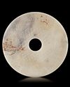 A CHINESE BI DISC DECORATED WITH A BORDER OF FOUR ANIMAL HEADS INTERTWINED TO FORM A PATTERN, LATE EASTERN ZHOU OR HAN PERIOD (c.471-221 BC)