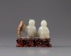 A pale jade carving of two boys with a wooden stand
