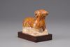 An earthenware figure of a ram on a wooden base