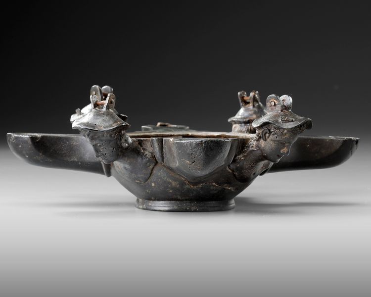 A ROMAN BRONZE OIL LAMP WITH FOUR SPOUTS AND BUSTS OF MERCURY, CIRCA 1ST-2ND CENTURY A.D