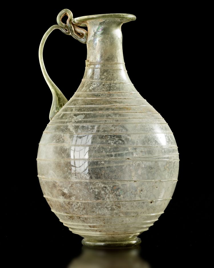 A ROMAN LIGHT GREEN GLASS JUG,1ST CENTURY A.D.