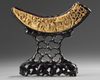 A Chinese carved boar's tusk on a wood stand