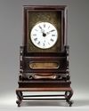 A Chinese gilt bronze table clock in a hongmu case and stand