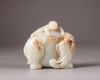 A Chinese pale celadon and russet jade boy and elephant group