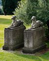 A PAIR OF SCULPTED LIMESTONE MODELS OF RECUMBENT HOUNDS