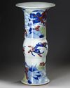 A CHINESE UNDERGLAZE BLUE, COPPER-RED AND CELADON-GLAZED CARVED BEAKER VASE, GU
