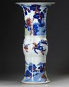 A CHINESE UNDERGLAZE BLUE, COPPER-RED AND CELADON-GLAZED CARVED BEAKER VASE, GU