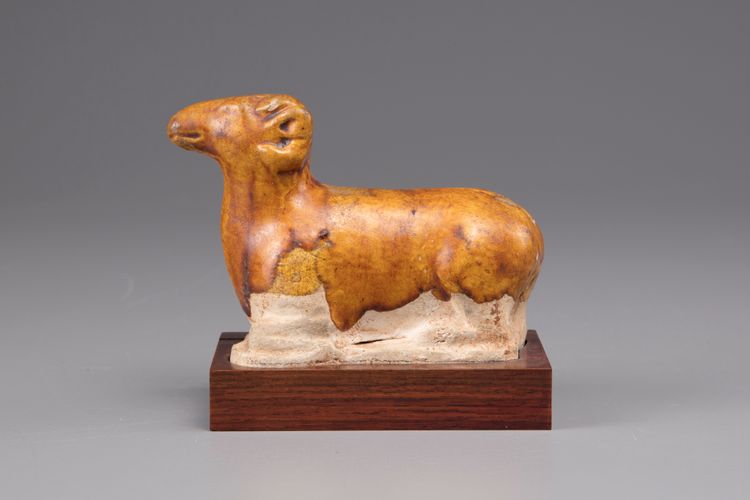 An earthenware figure of a ram on a wooden base