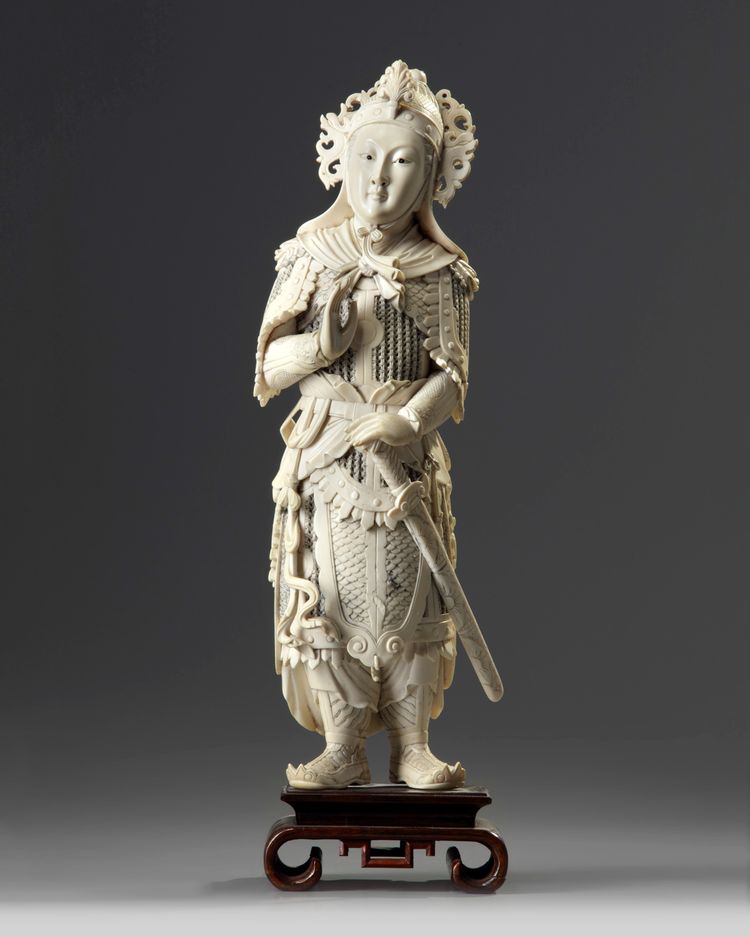 A large Chinese carved ivory figure of a guardian