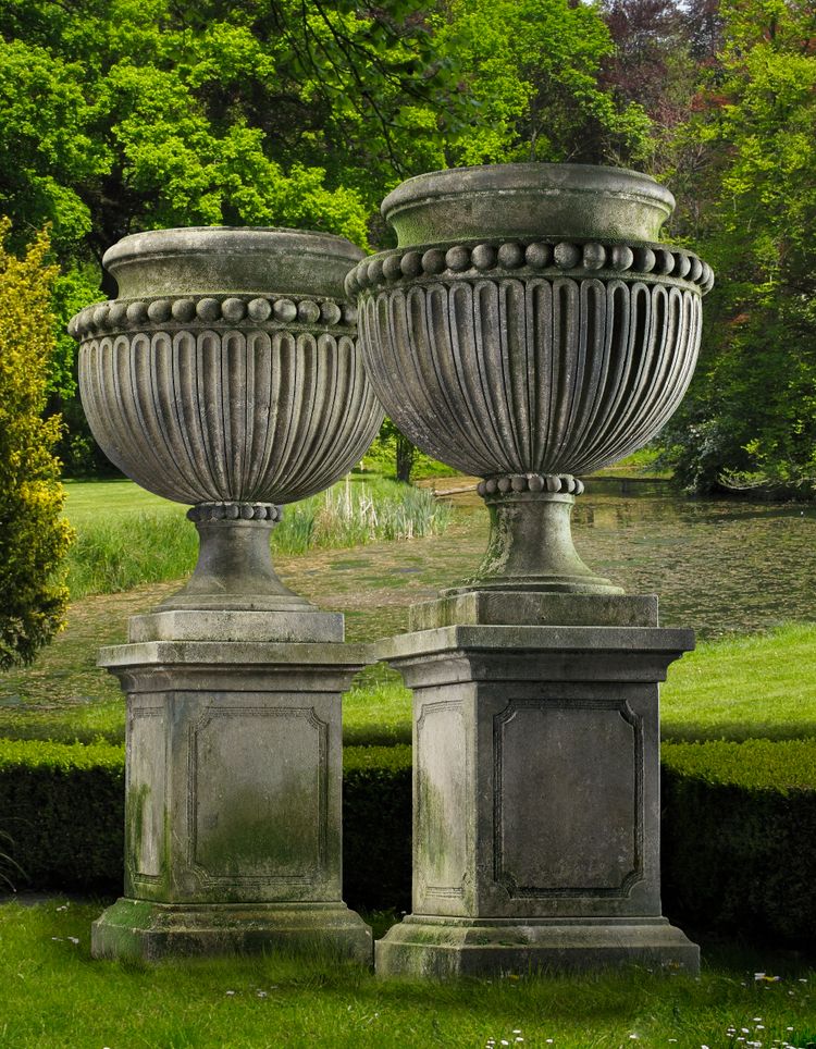 A PAIR OF LARGE AND IMPRESSIVE CARVED LIMESTONE GARDEN URNS ON PLINTHS IN IMPERIO TASTE, LATE 20TH CENTURY