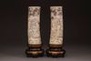 A pair of Japanese carved tusks on a wooden base