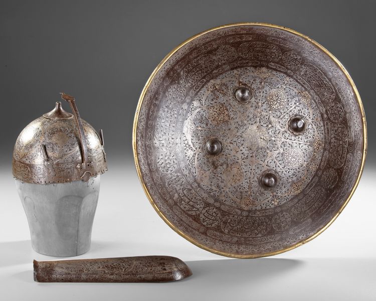 A PERSIAN GILT DAMASCENED HELMET, SHIELD AND ARM-GUARD, QAJAR 19TH CENTURY