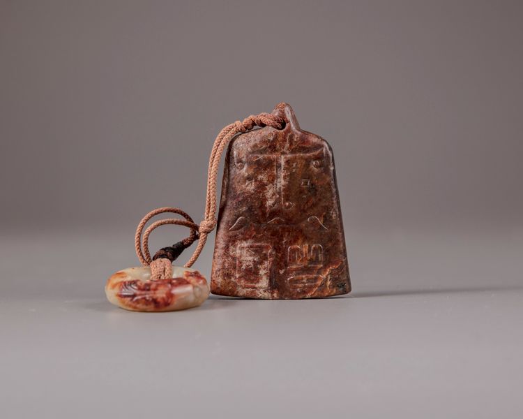 A Chinese celadon and russet jade disc and a brown jade pendant
