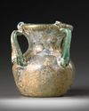 A ROMAN FOUR-HANDLED GREEN GLASS JAR, CIRCA 3RD CENTURY A.D.